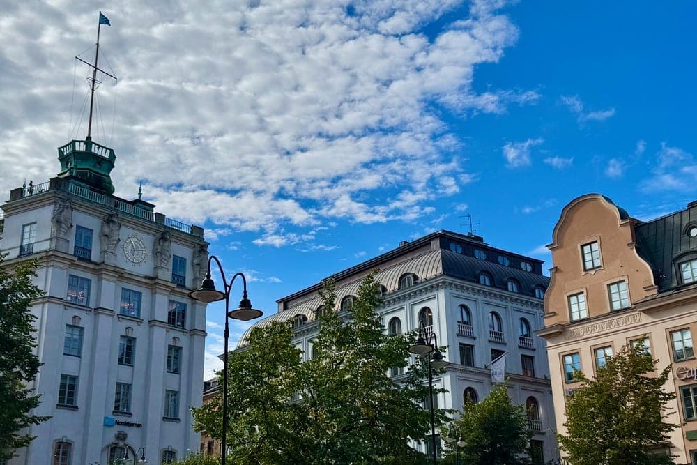Buildings in Stockholm, Sweden, with a prominent tower and varied facades, set against a blue sky with white clouds.