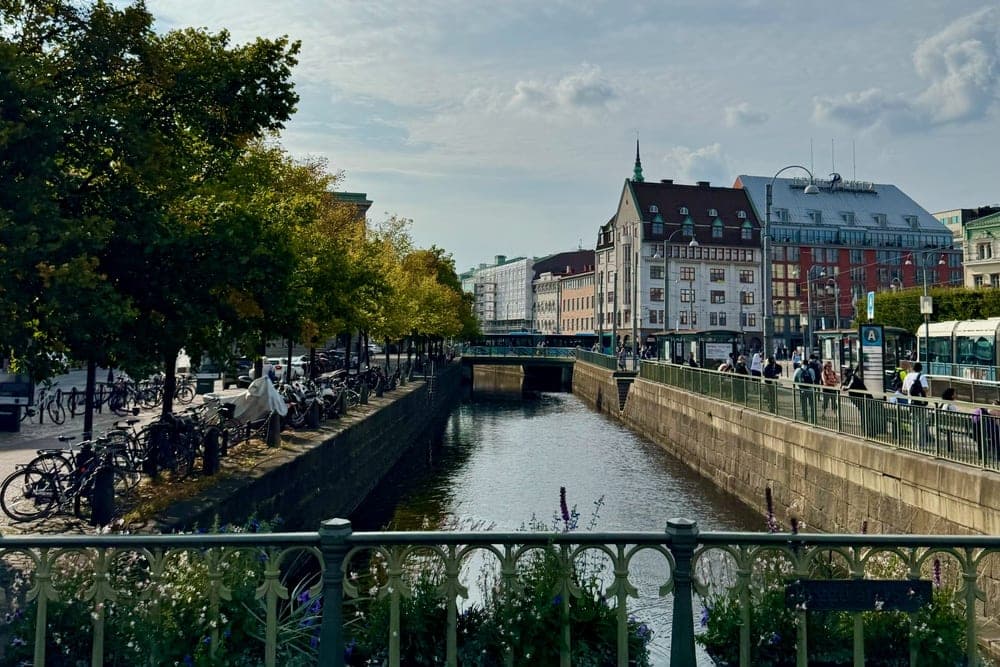A canal in Göteborg, Sweden, with trees and parked bicycles on one side and buildings and a pedestrian walkway on the other.