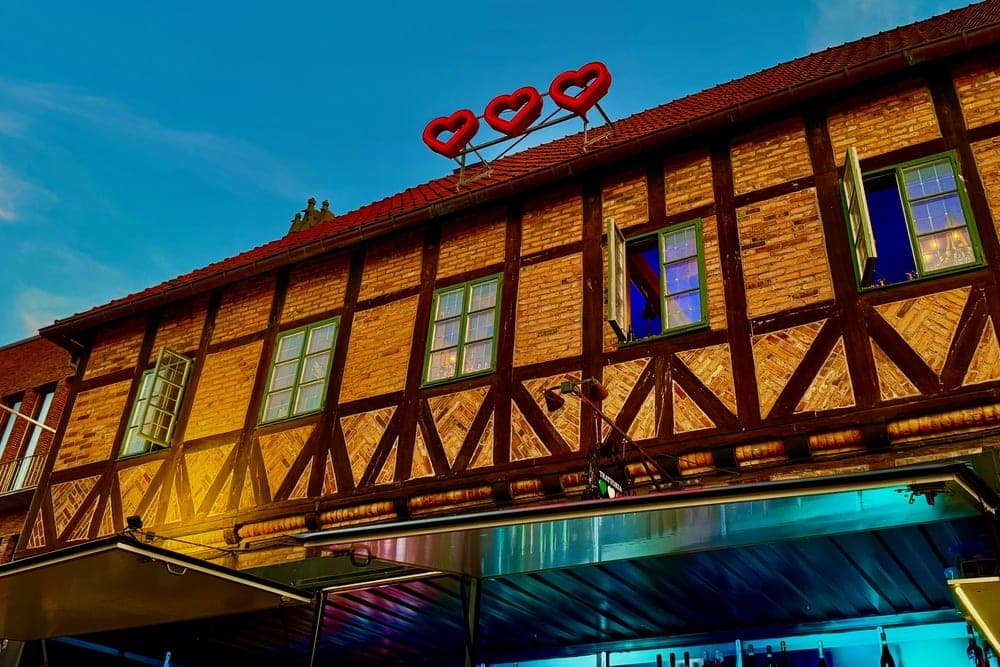 A building with red heart balloons on the roof in Halmstad, Sweden, illuminated by colorful lights.