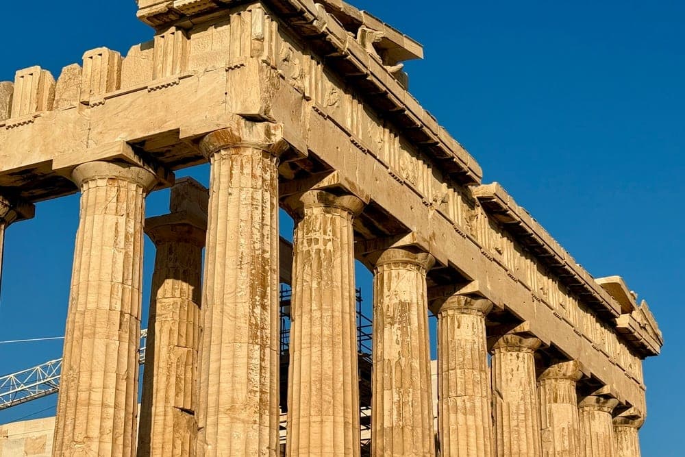 The Parthenon in Athens, Greece, with its massive stone columns reaching towards a clear blue sky.