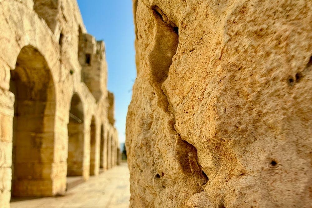 A close-up view of ancient stone arches in Athens, Greece, with a textured column in the foreground.