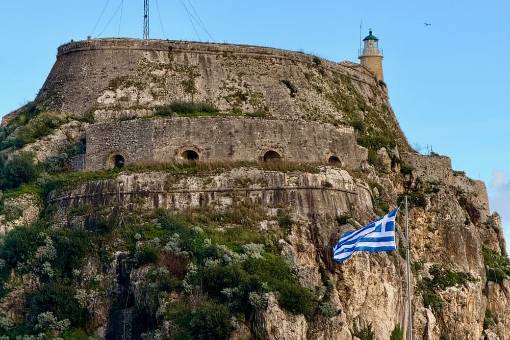 The Old Fortress of Corfu, Greece, with the Greek flag flying prominently in front.