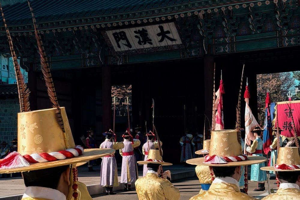 Guards in traditional golden robes and feathered hats at Deoksugung Palace in Seoul, South Korea.