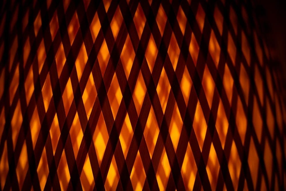 Close-up of a woven bamboo lantern with warm orange light shining through its diamond pattern, San Francisco, United States.
