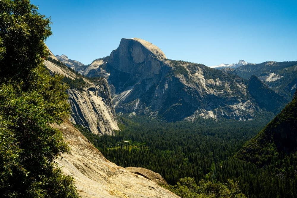 Half Dome mountain towering over Yosemite Valley, United States, with dense pine forests below and granite cliffs to the sides.
