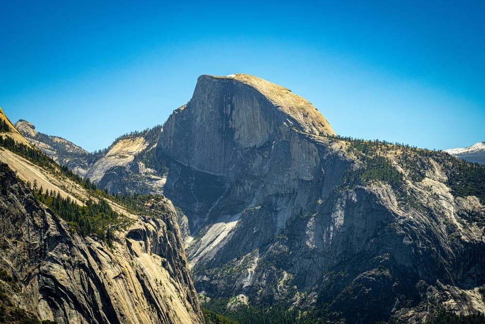 The granite monolith of Half Dome stands prominently in Yosemite National Park, California, United States, under a clear blue sky.