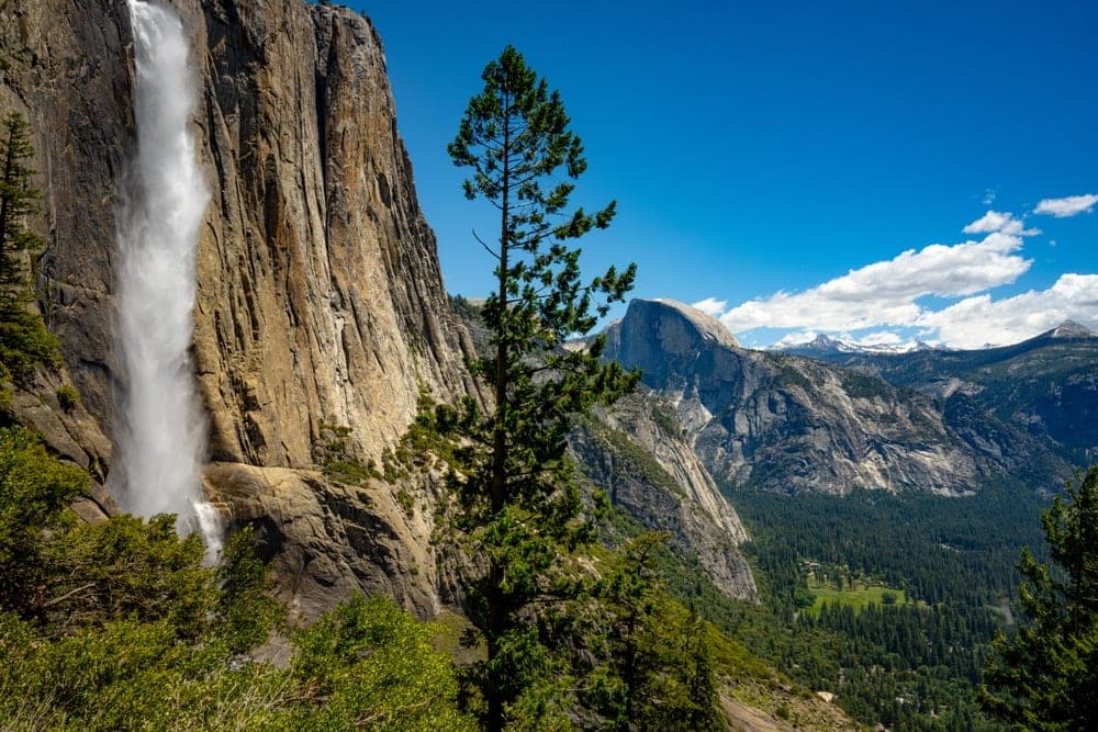 Yosemite Falls cascading down a granite cliff in Yosemite National Park, United States, with Half Dome in the background.
