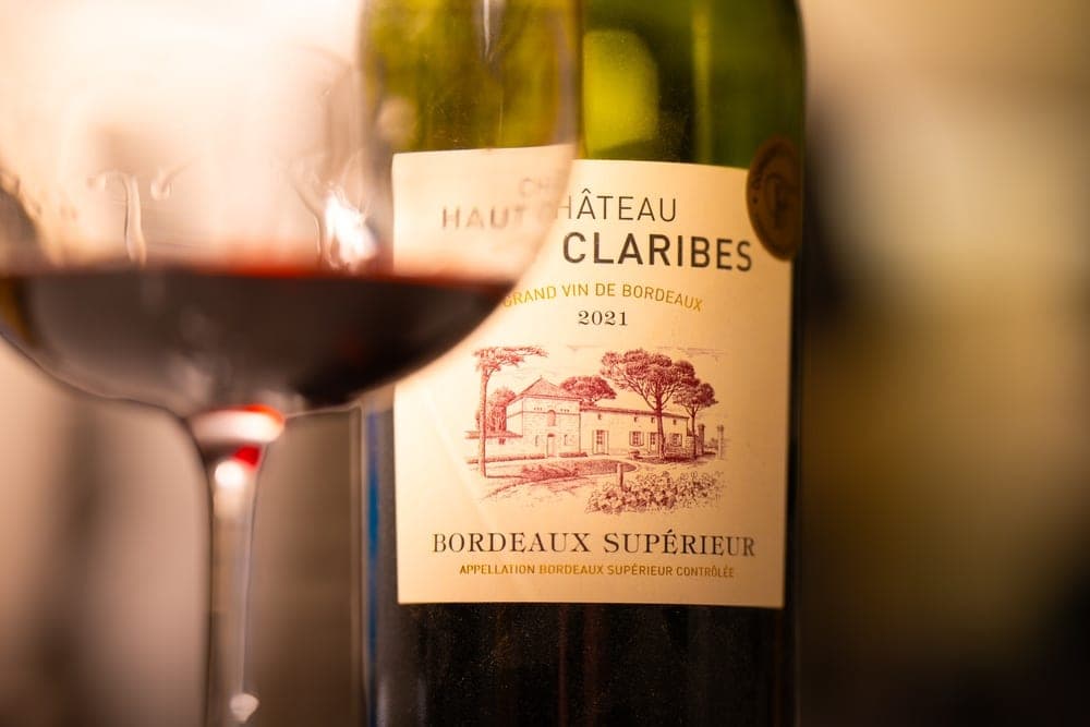 A close-up of a bottle of Château Claribes Bordeaux wine and a glass of red wine in Sunnyvale, California, United States.