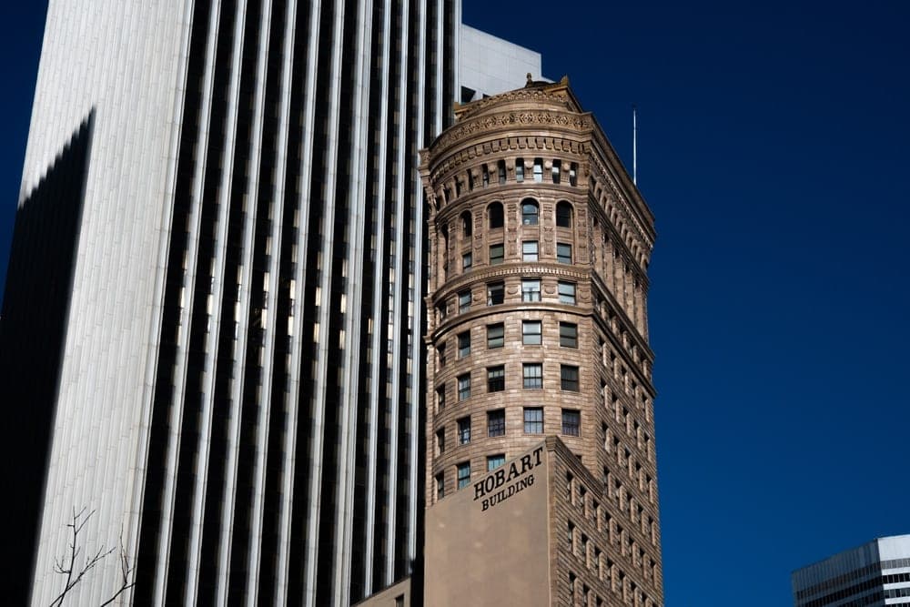 The historic Hobart Building in San Francisco, United States, stands next to a modern skyscraper against a clear blue sky.