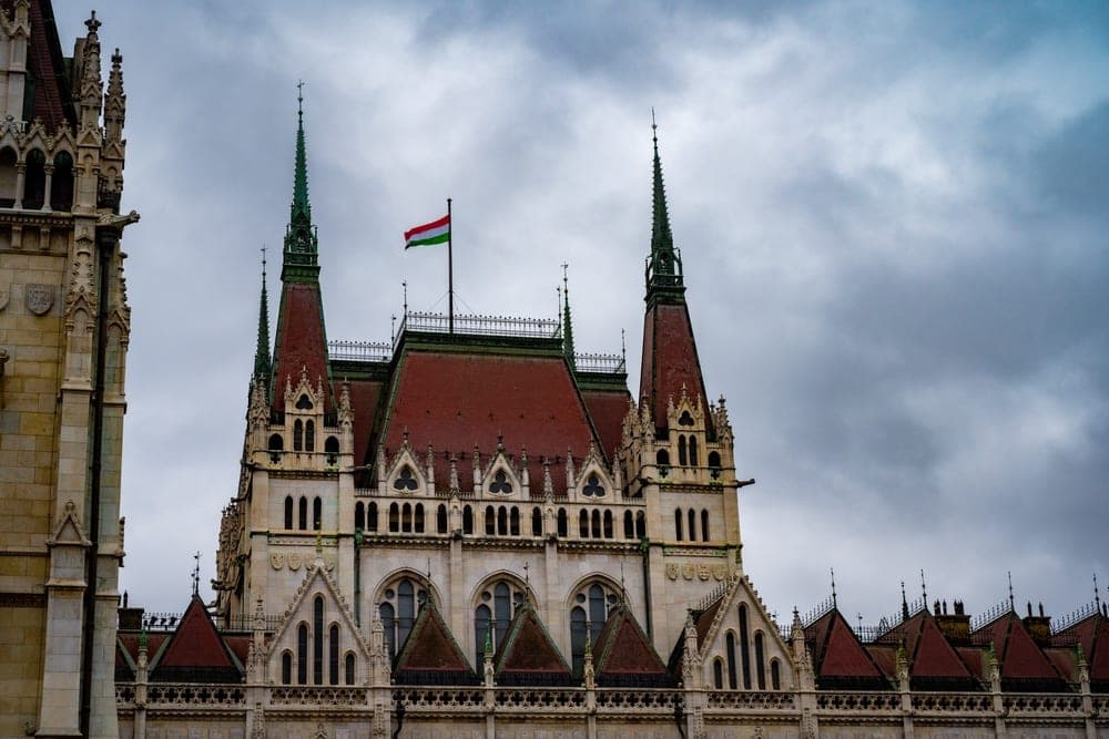 The Hungarian Parliament Building in Budapest, Hungary, under a cloudy sky.