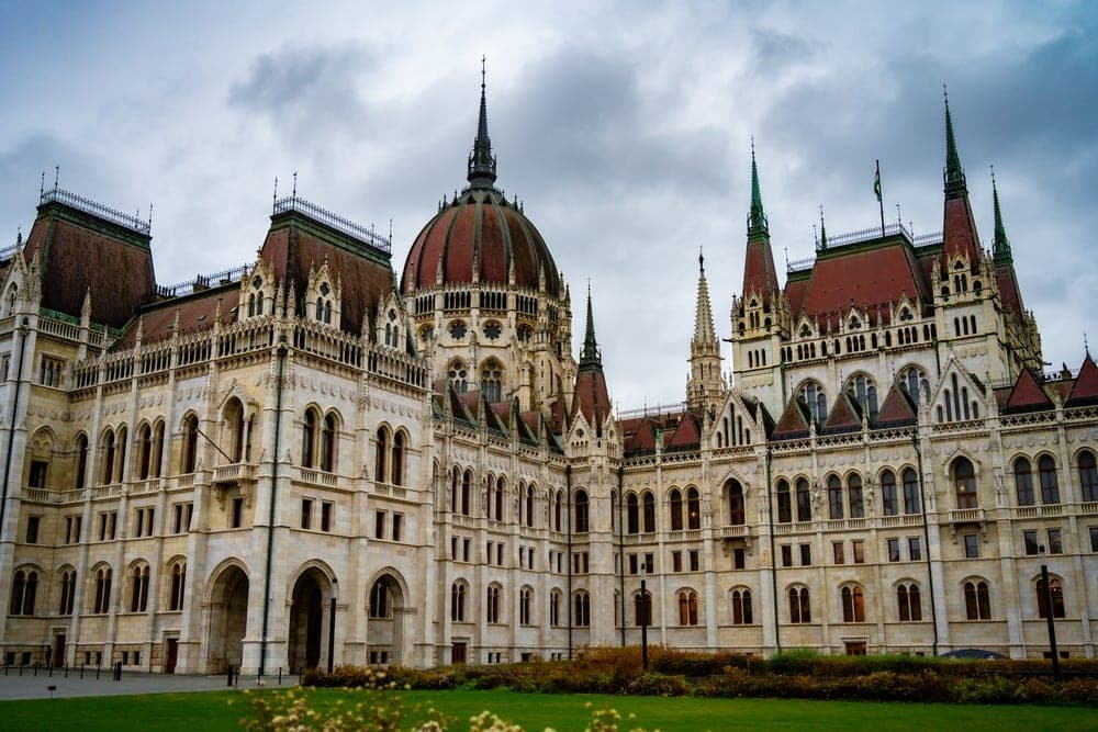 The Hungarian Parliament Building in Budapest, Hungary, under a cloudy sky.