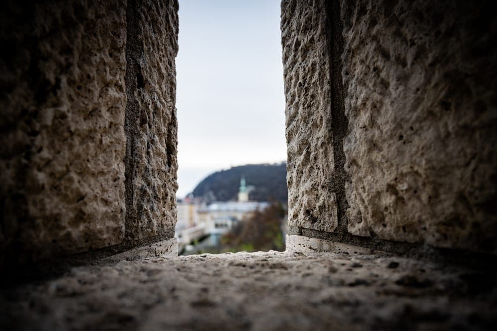 View through a stone embrasure of Budapest, Hungary, with a distant hill and spire.