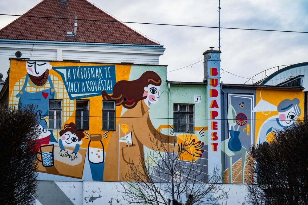 A colourful mural on a building in Budapest, Hungary, depicting people and text.