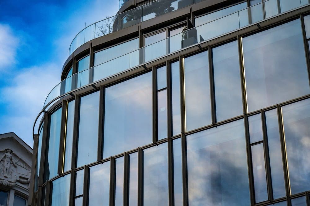A modern curved glass building in Budapest, Hungary, reflecting a blue sky with clouds.