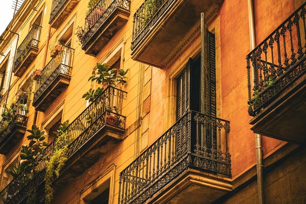 Wrought-iron balconies overflow with plants on ochre-coloured buildings in Barcelona, Spain.