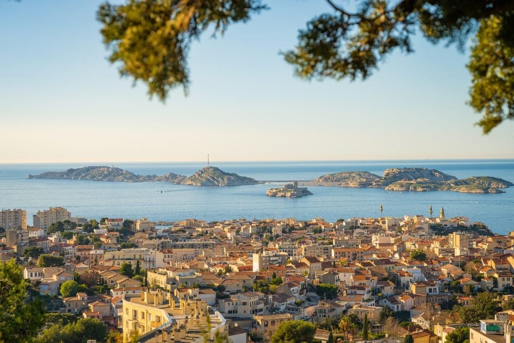 Panoramic view of Marseille, France, with its terracotta rooftops and the Mediterranean Sea with islands and the Château d'If.