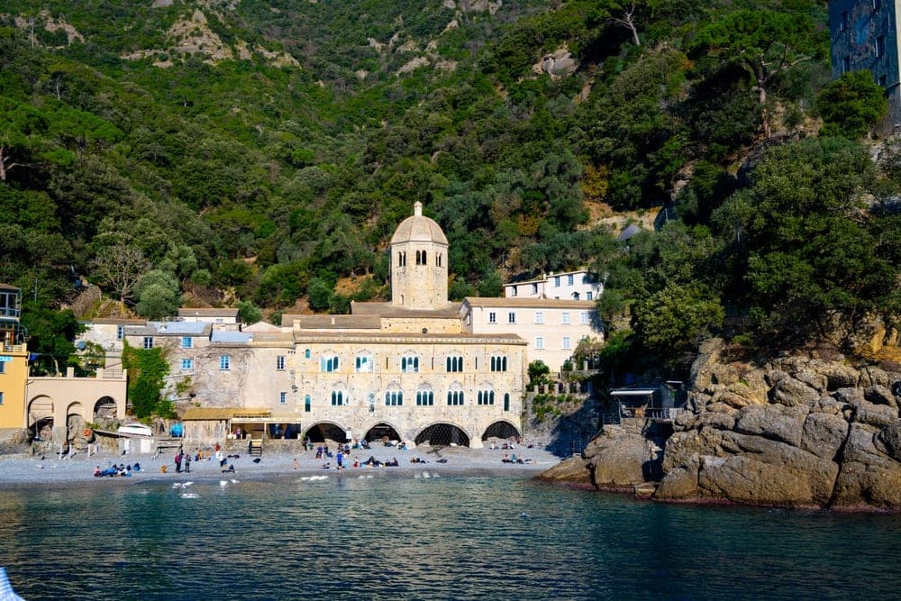 The San Fruttuoso Abbey on the coast of Camogli, Genoa, Italy, with a pebble beach and the Mediterranean Sea.