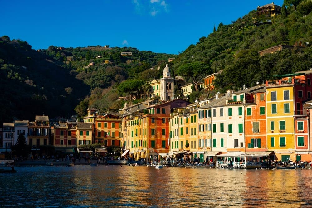Colorful buildings lining the harbor of Portofino, Italy, under a clear blue sky.