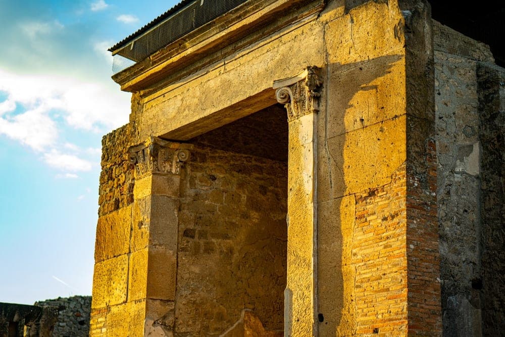 Ancient Roman doorway in Pompeii, Italy, bathed in golden afternoon light.
