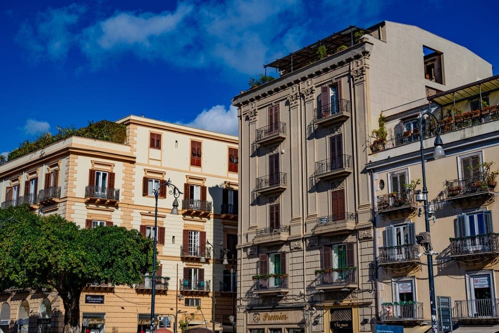 Historic buildings with balconies and shutters on a street in Palermo, Italy.