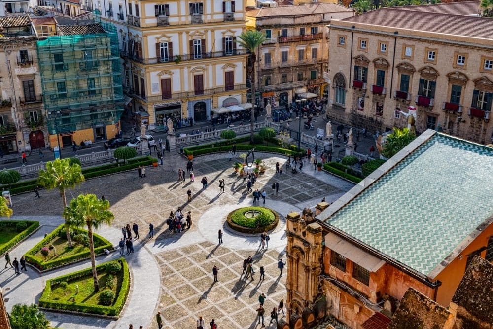 Aerial view of Piazza Pretoria in Palermo, Italy, with people walking and historic buildings surrounding the square.