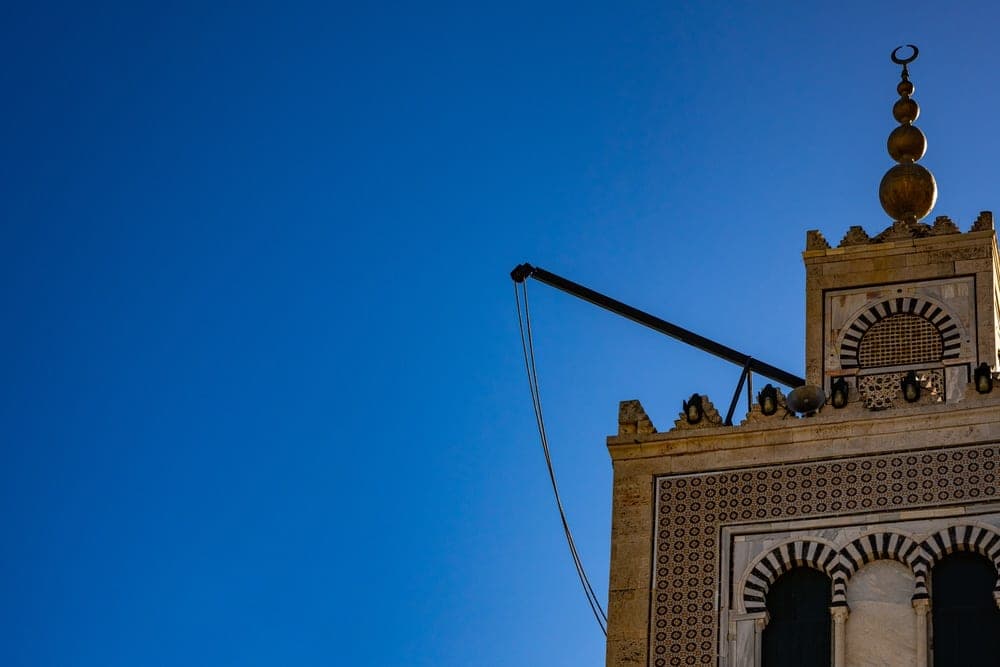 Detail of a minaret with intricate geometric carvings and a golden finial in Tunis, Tunisia.