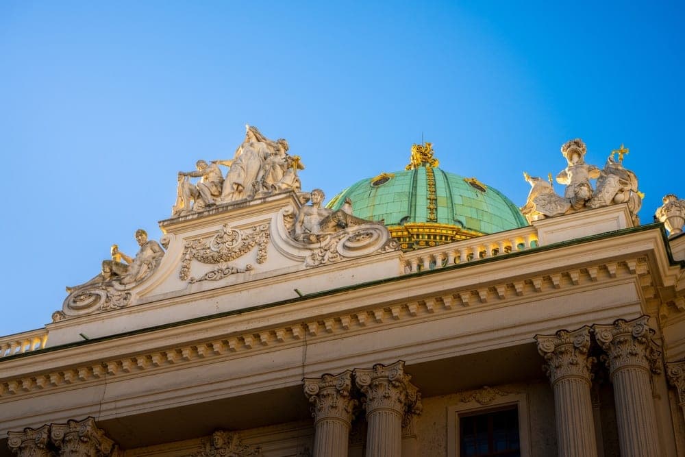 Ornate classical architecture with a green dome and sculptures in Vienna, Austria.