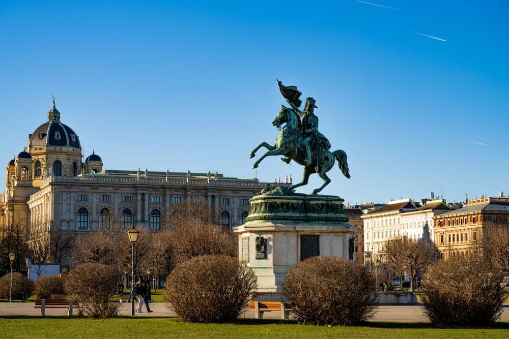 Equestrian statue of Prince Eugene of Savoy in front of historical buildings in Vienna, Austria, under a clear blue sky.